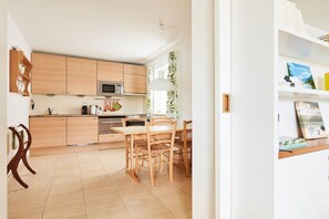 Eine moderne Küche mit Holzausstattung, einer Mikrowelle und einem Essbereich mit Tisch und Stühlen.