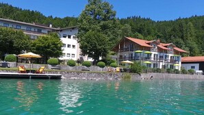 Ein Hotel am Seeufer mit Sitzgelegenheiten im Freien, einem Pool und Gebäuden mit Balkonen.
