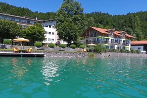 Ein Hotel am Seeufer mit Sitzgelegenheiten im Freien, einem Pool und Gebäuden mit Balkonen.
