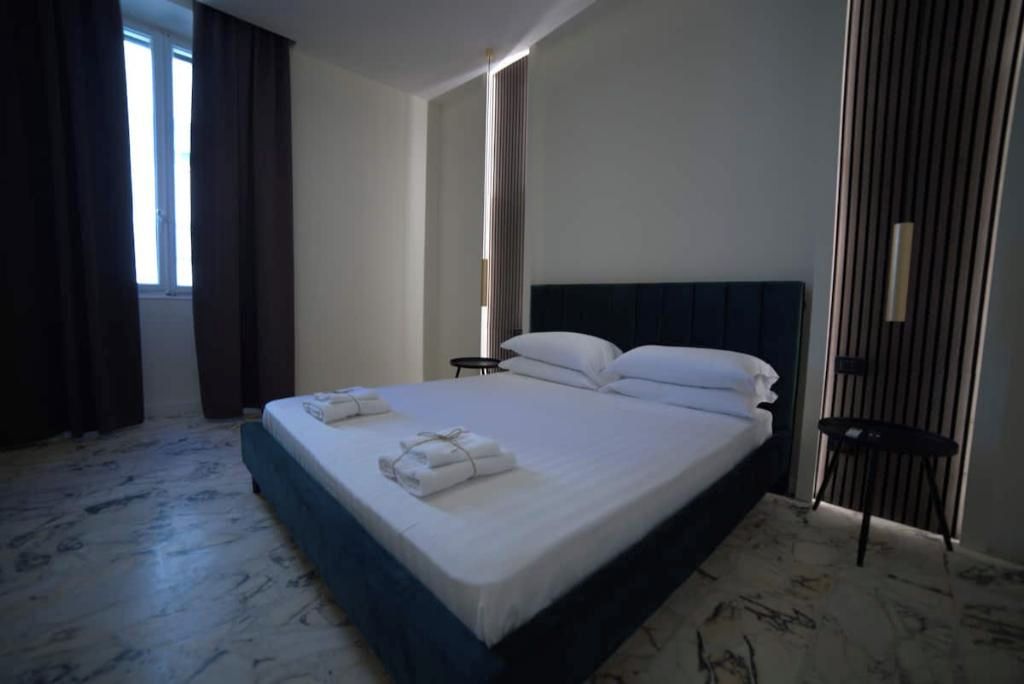 A hotel room with a large bed, a bedside table, and a view of the outdoors.
