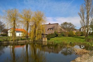 En fridfull miljö vid en sjö med traditionella hus, ett stilla vatten och en klar himmel.