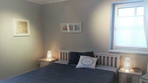 Ett sovrum med en säng, sängbord, ett fönster och konst på väggen.