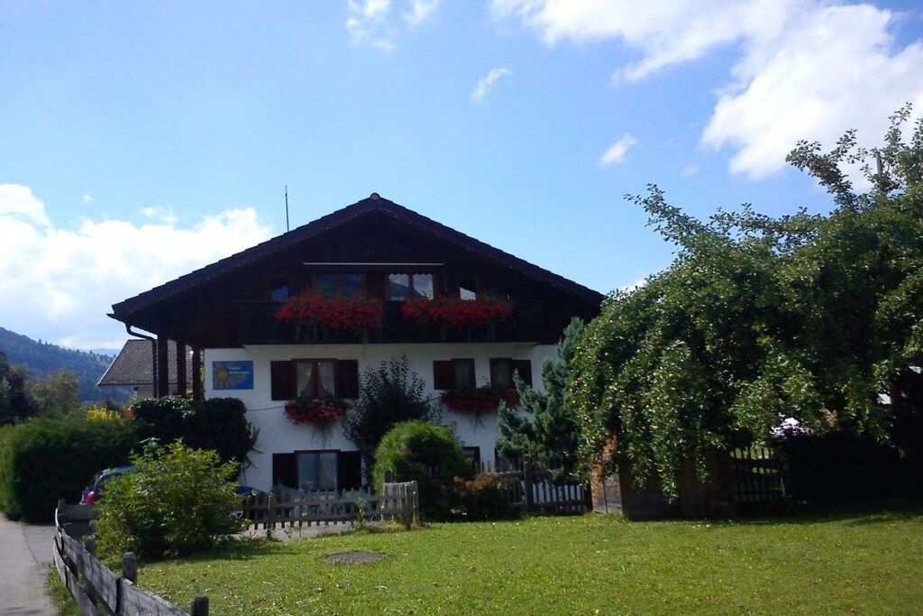 A two-story building with a sloped roof, a wooden fence, and a grassy lawn.