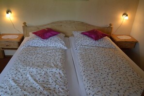 A double bed with floral bedding and two pillows, flanked by nightstands with lamps. - at the E. Schmid guesthouse (Bad Hindelang)