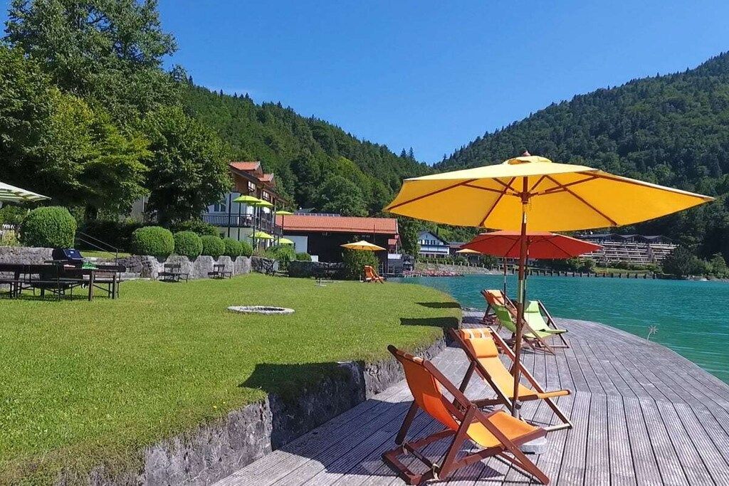 Terraza junto al lago con mobiliario exterior y vista al agua.