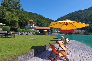 Terraza junto al lago con mobiliario exterior y vista al agua.