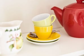 A stack of yellow cups on a white plate with a red teapot beside them. - No. 3 - The Lake House (Walchensee)