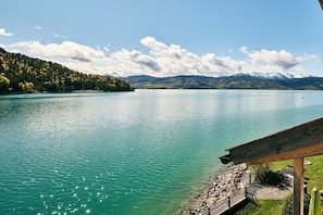 A lakeside view with a wooden deck and a stone pathway leading to a seating area. - No. 3 - The Lake House (Walchensee)