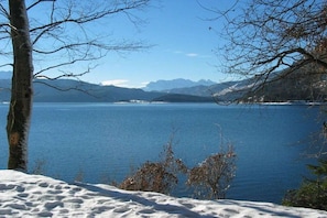 A snow-covered landscape with a clear view of a lake and distant mountains. - No. 3 - The Lake House (Walchensee)