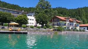 Ein Seehotel mit Steg, Sitzgelegenheiten im Freien und Blick auf den umliegenden Wald.