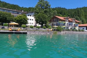 Ein Seehotel mit Steg, Sitzgelegenheiten im Freien und Blick auf den umliegenden Wald.