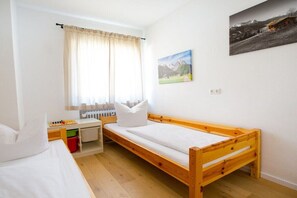 Ein Schlafzimmer mit einem hölzernen Bett, einem Schreibtisch mit Stuhl, einem Heizkörper und einem Fenster mit Vorhängen.