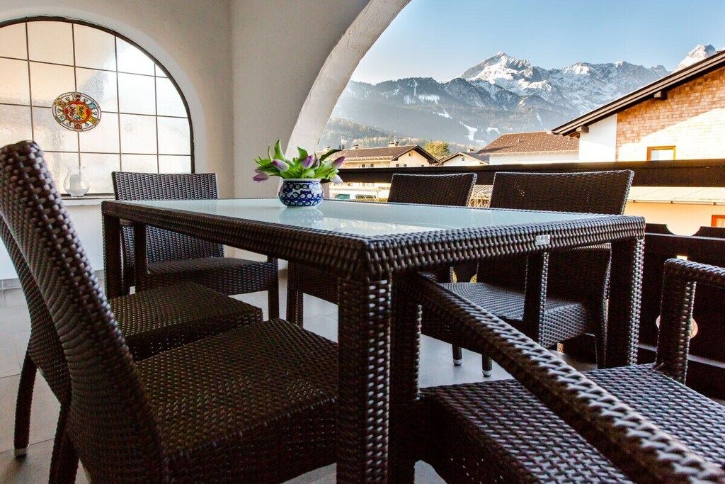 Comedor con mobiliario de mimbre y vistas a montañas nevadas.