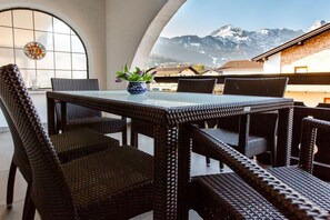Ein Essbereich mit Korbmöbeln und Blick auf schneebedeckte Berge.