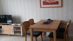 En matplats med ett träbord och stolar, en tv-apparat på ett skåp och en inramad tavla på väggen.