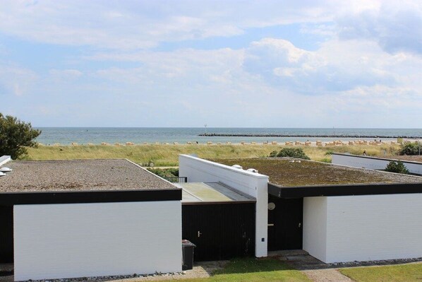 A coastal view with a beach and a pier in the distance. There are white buildings with flat roofs in the foreground. - Holiday apartment with 1 bedroom (Fehmarn)