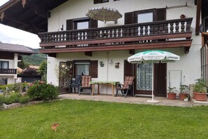 A building with a balcony, outdoor seating, and a sign indicating a beer garden. - Haus Berggruß EG with Chiemgau map (Ruhpolding)