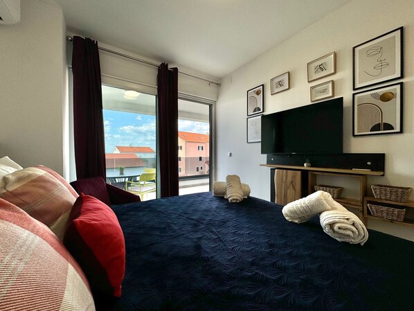 Une chambre d’hôtel avec un lit, une télévision et une fenêtre avec des rideaux.