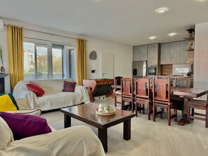 Un salon comprenant un canapé, une table basse et un coin repas avec des chaises et une table en bois.