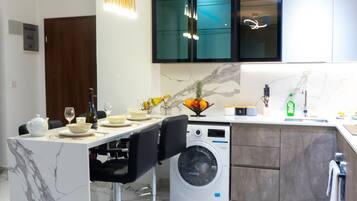 Una cocina moderna con una isla de mármol, lavadora e iluminación colgante.