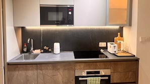 A modern kitchen with a built-in microwave, oven, and a sink. - Peravi at The Essence  (Accra)