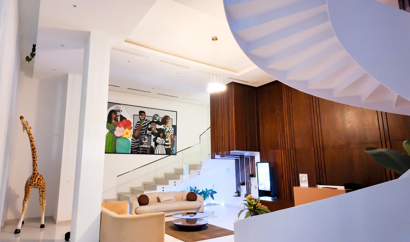 Un interior moderno con una escalera, un mostrador de recepción y una escultura de jirafa.