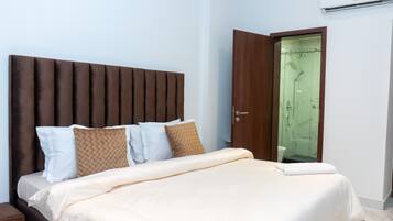 Un dormitorio con cama, almohadas, cabecero de madera, una puerta y un equipo de aire acondicionado.