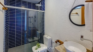 Ein Badezimmer mit Duschkabine, Toilette, Waschbecken und Spiegel.