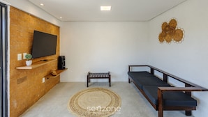 Una sala de estar moderna con una pared de madera, un televisor de pantalla plana, un pequeño banco, un sofá y un adorno mural.