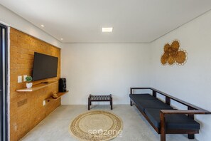 Una sala de estar moderna con una pared de madera, un televisor de pantalla plana, un pequeño banco, un sofá y un adorno mural.