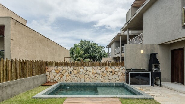 Ein Garten mit Swimmingpool, Steinmauer, Holzterrasse und Grillplatz.
