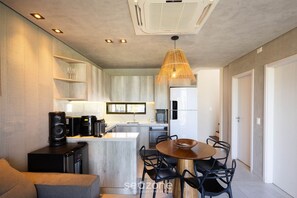 Et moderne køkken med en central ø, indbyggede apparater og et spiseområde med et rundt bord og stole.