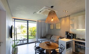 Eine moderne Küche mit Einbauherd, Mikrowelle und Backofen. Es gibt einen Essbereich mit einem runden Holztisch und Stühlen, sowie ein großes Fenster mit Blick ins Freie.