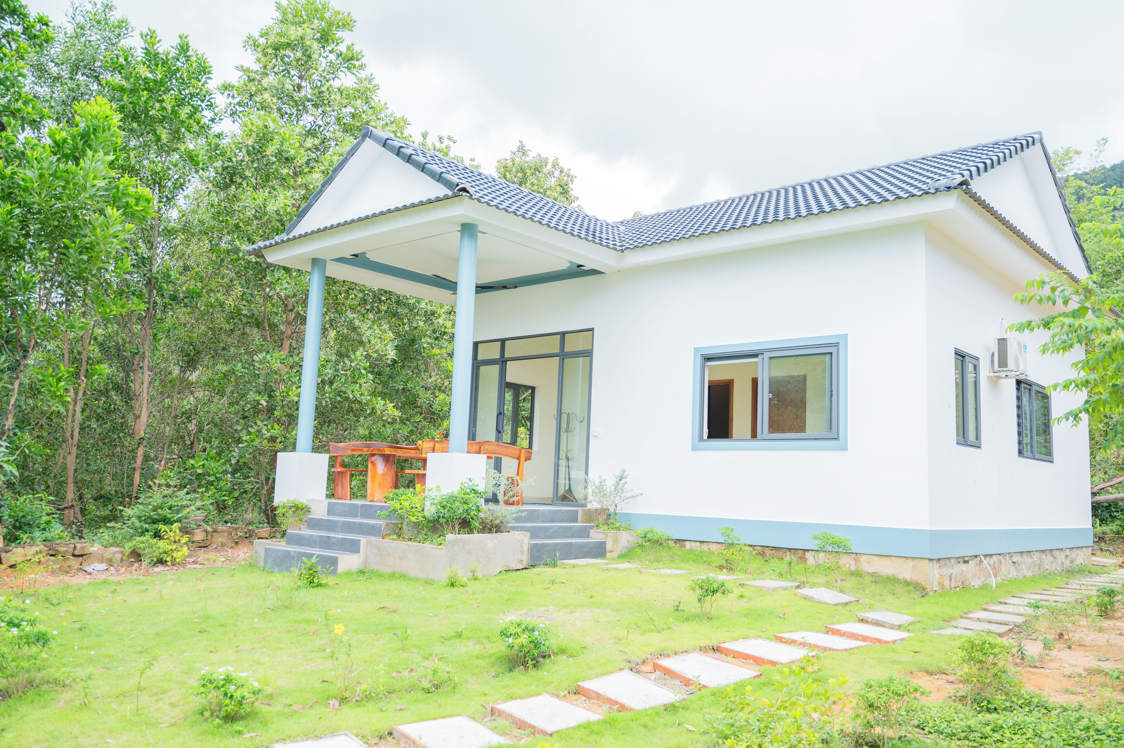A modern two-story house with a covered porch, a front entrance, and a garden area.