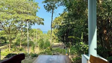An outdoor seating area with a bench and a table, surrounded by trees and vegetation.