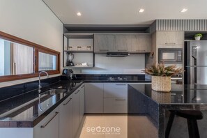 A modern kitchen with a black countertop, stainless steel appliances, and a built-in oven. - House in Arraial D'ajuda With Pool Pcr0009 (Porto Seguro)