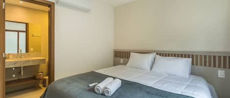 Habitación de hotel con cama, baño con lavamanos y espejo, y unidad de aire acondicionado.