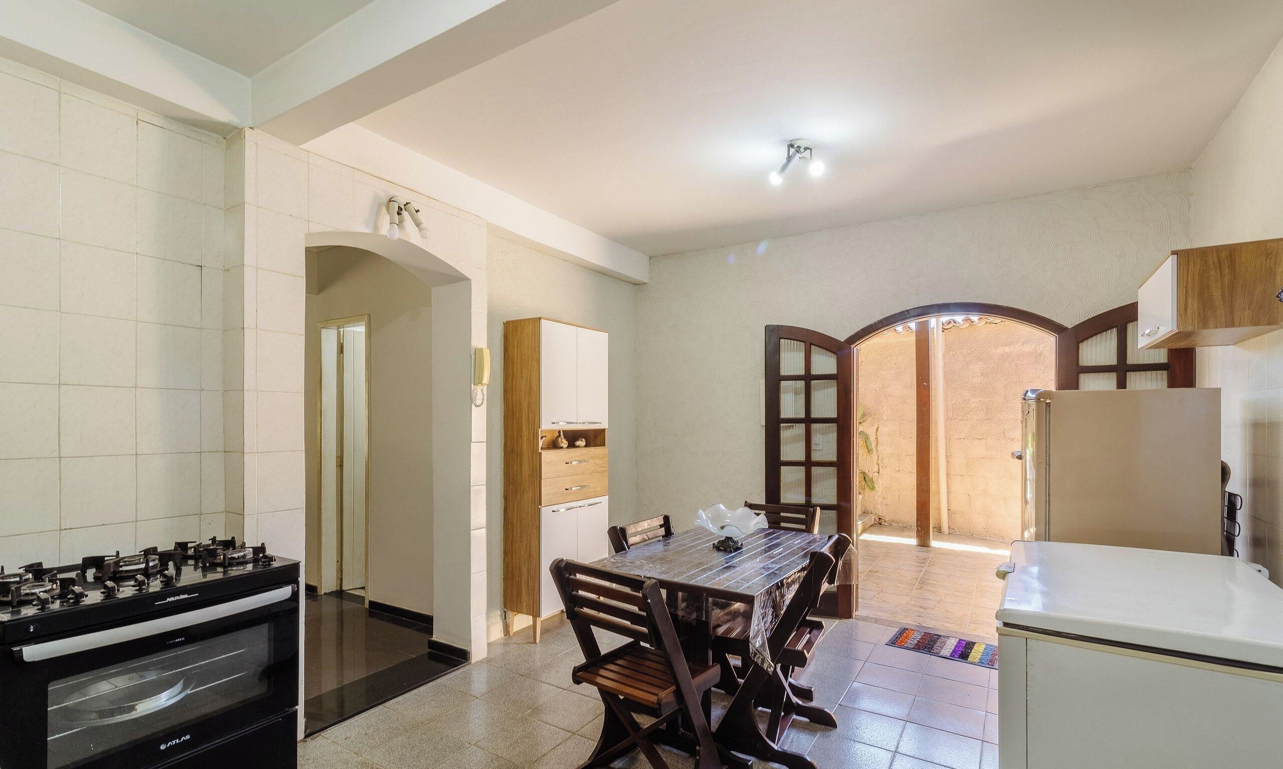 Una cocina con estufa a gas, una mesa de comedor con sillas y un refrigerador.