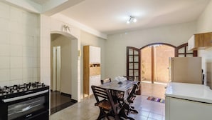 A kitchen with a gas stove, a dining table with chairs, and a refrigerator. - House in Cond. w/ Pool - Cabo Frio Vdp0029 (Cabo Frio)