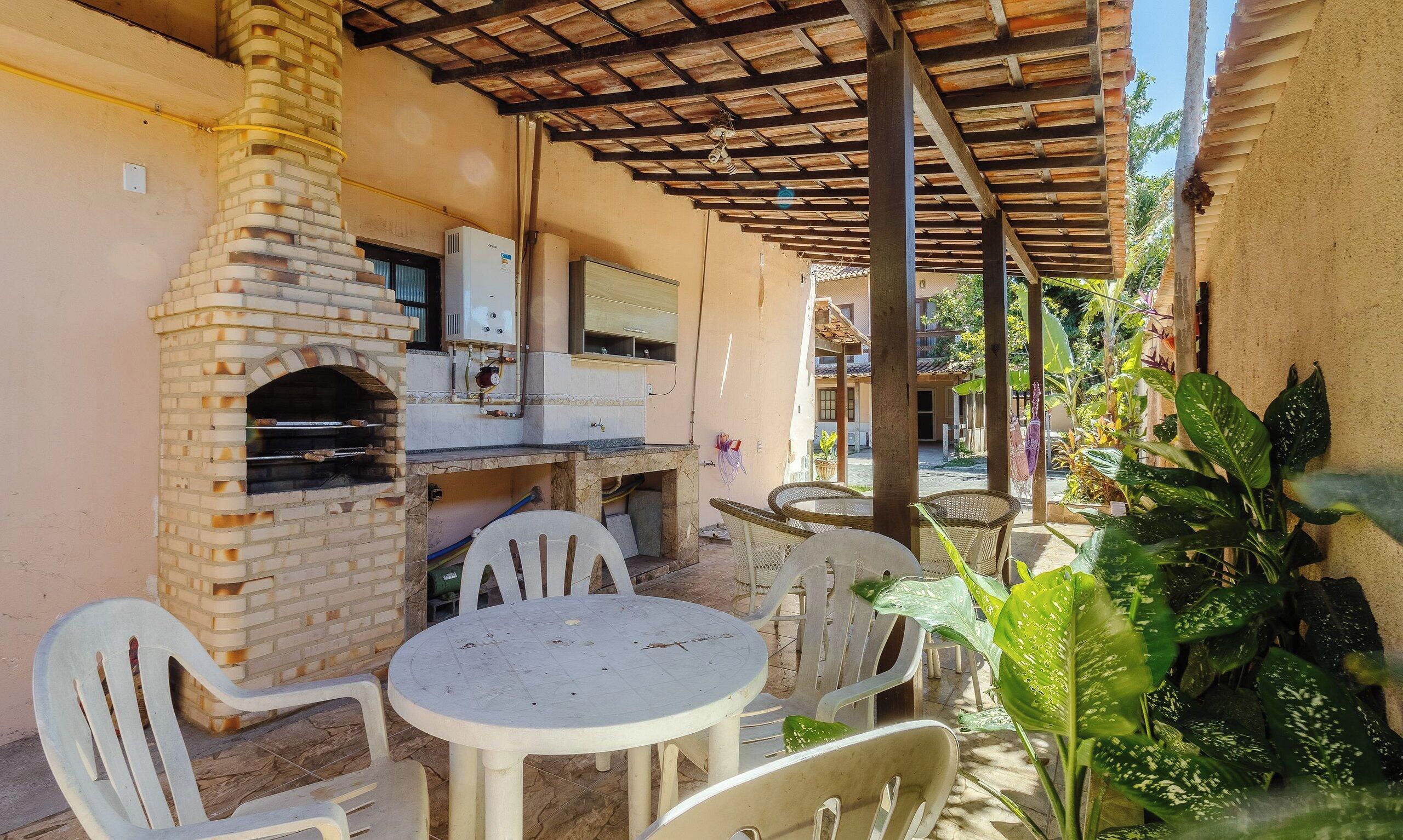 Un patio al aire libre con horno de ladrillo, calentador de agua y suelo de baldosas.