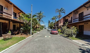 Un carrer residencial amb cases, palmeres i un cotxe vermell aparcat al costat.