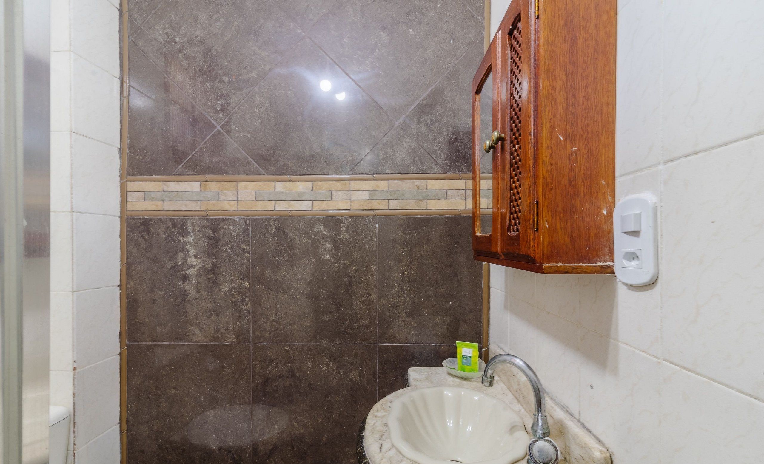 A bathroom with a sink, mirror, and a wooden cabinet.