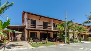 A two-story building with a balcony, outdoor seating, and tropical plants. - House in Cond. w/ Pool - Cabo Frio Vdp0029 (Cabo Frio)