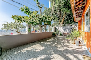 A paved outdoor area with a view of the sea, surrounded by trees and potted plants. - TOP and Cozy Apartment Facing the Lagoon Sdr001 (Florianópolis)