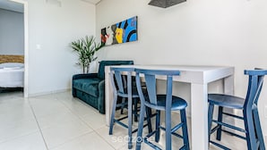 A modern dining area with a white table and blue chairs, a painting on the wall, and a plant. - TOP and Cozy Apartment Facing the Lagoon Sdr001 (Florianópolis)
