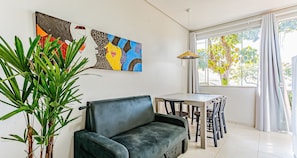 A room with a sofa, a dining table with chairs, a potted plant, and artwork on the wall. - TOP and Cozy Apartment Facing the Lagoon Sdr001 (Florianópolis)