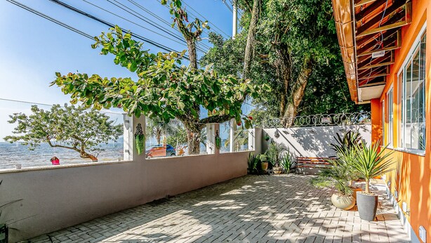 A paved outdoor area with a view of the sea, surrounded by trees and potted plants. - TOP and Cozy Apartment Facing the Lagoon Sdr001 (Florianópolis)