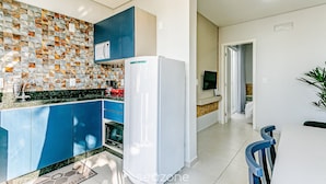 A modern kitchen with blue cabinets, a white refrigerator, and a tiled backsplash. - TOP and Cozy Apartment Facing the Lagoon Sdr001 (Florianópolis)