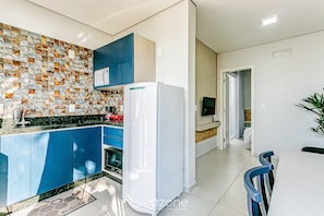 Eine moderne Küche mit blauen Schränken, einem weißen Kühlschrank und einer gefliesten Spritzschutzwand.