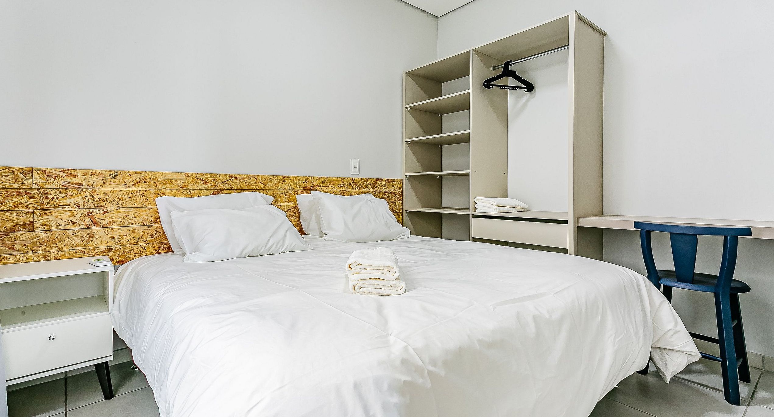 Ett hotellrum med en säng, ett nattduksbord, en garderob och ett skrivbord med en stol.